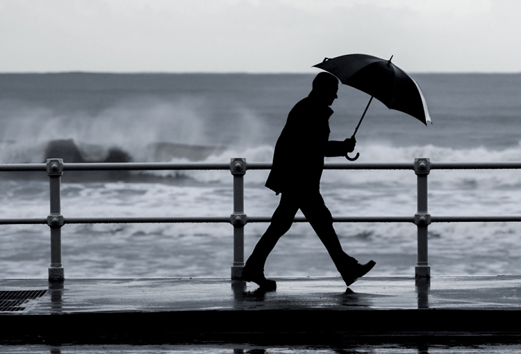 Persona paseando con un paraguas en un dia lluvioso