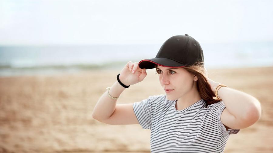 Mujer poniéndose una gorra en la playa