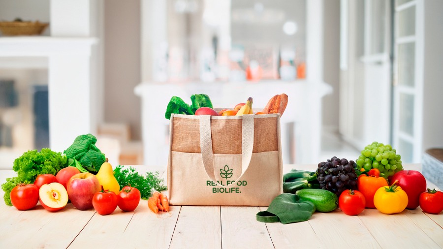 Una bolsa de yute para la compra al lado de una gran variedad de frutas y verduras